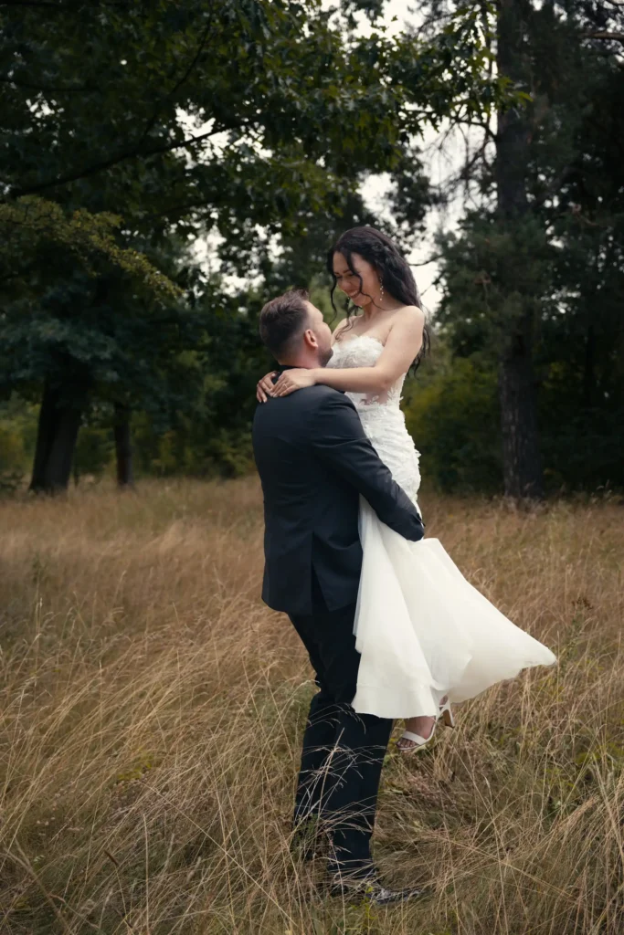 Bräutigam hebt die lachende Braut im hohen Gras hoch – Paarmotiv zur Hochzeit in Görlitz.